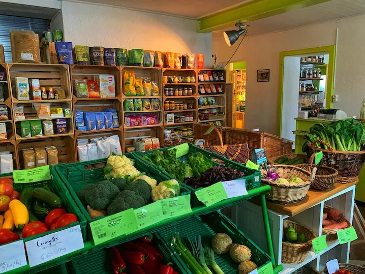 Intérieur du magasin avec une étale de produits bio, des légumes au premier plan